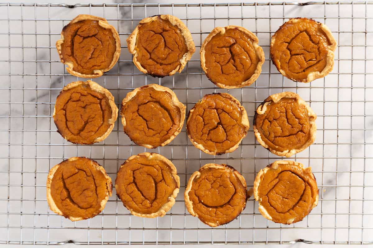 Mini pumpkin pies on cooling rack after baking.