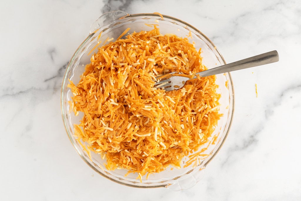 Mixture for sweet potato fritters in glass bowl.