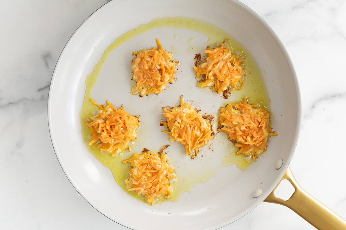 Sweet potato fritters in frying pan before flipping.