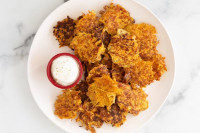 Sweet potato fritters on white plate with dip.