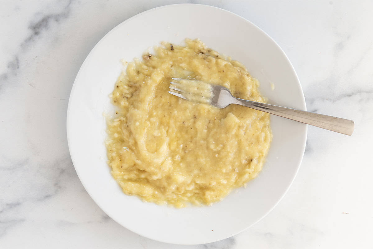 Banana being mashed in bowl for banana blondies.