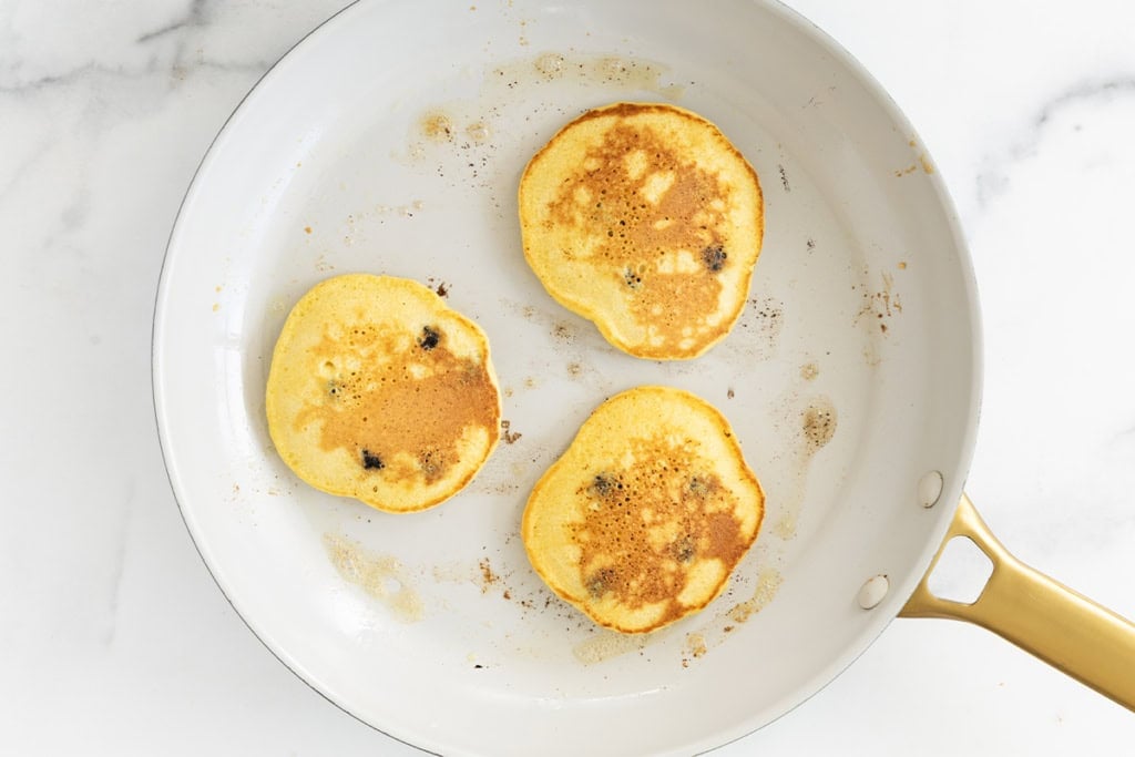 Cornmeal pancakes in pan after flipping.