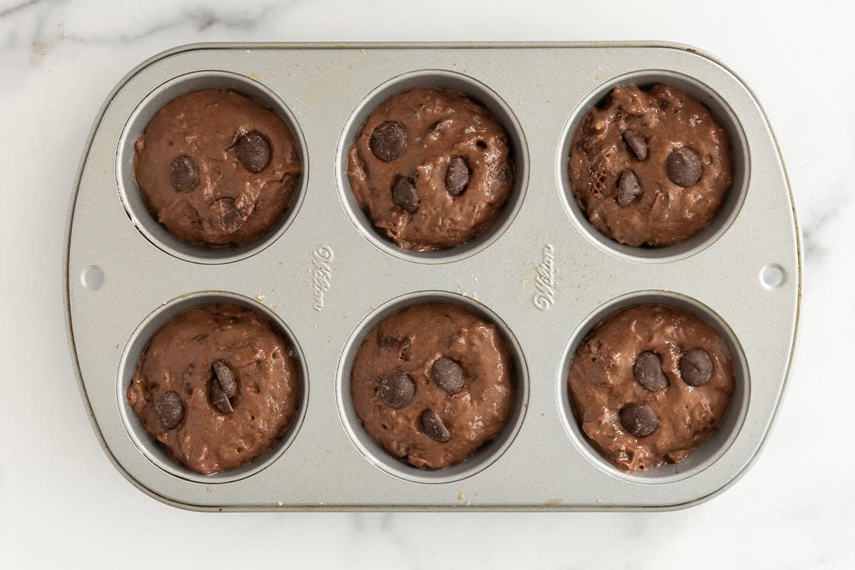 Batter in muffin pan for double chocolate muffins.