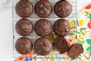 Double chocolate muffins on cooling rack with one cut open.