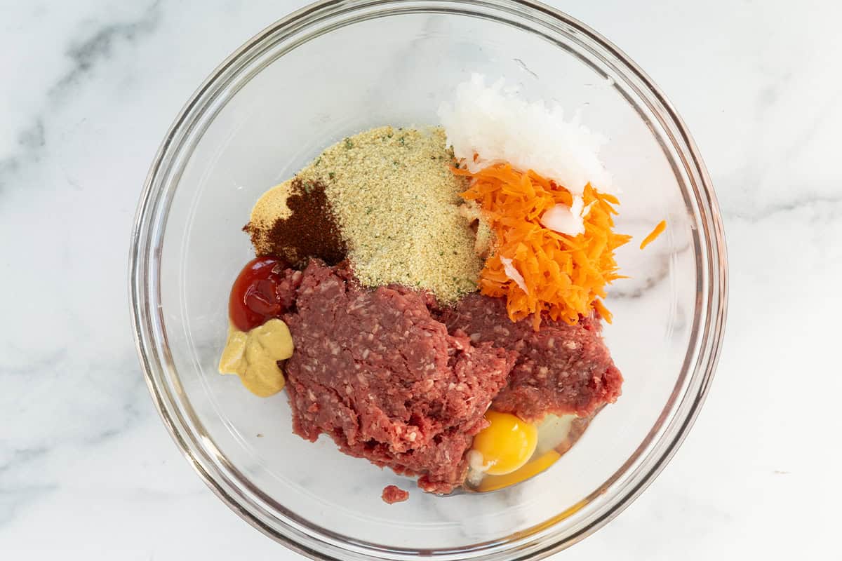 Ingredients for mini meatloaves in glass bowl before mixing.