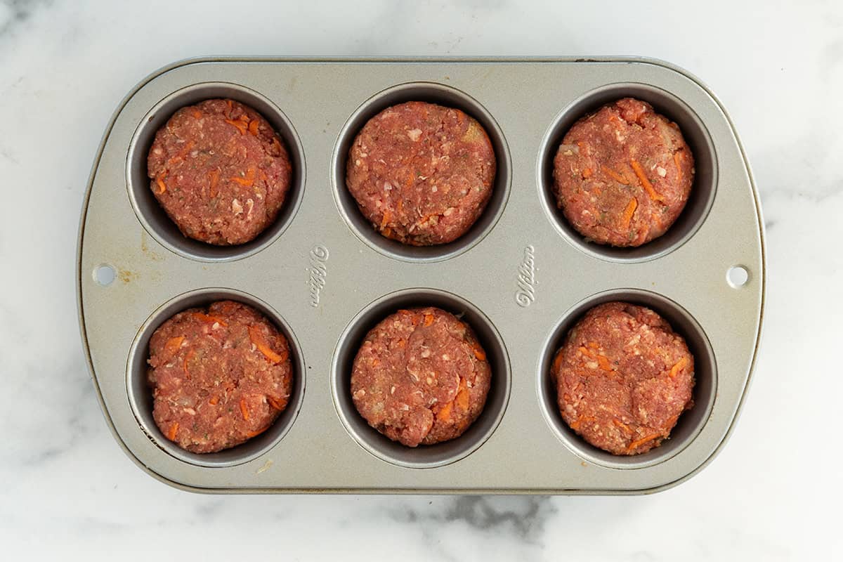 Mini meatloaves in muffin pan before baking.