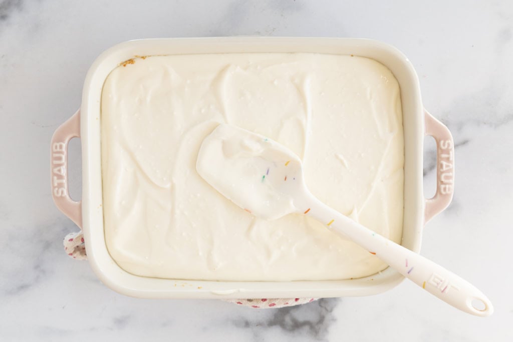 Spatula spreading yogurt mixture for no-bake cheesecake.