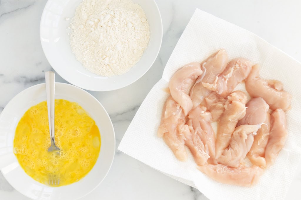 Chicken, egg and flour in separate bowls for air fryer chicken.