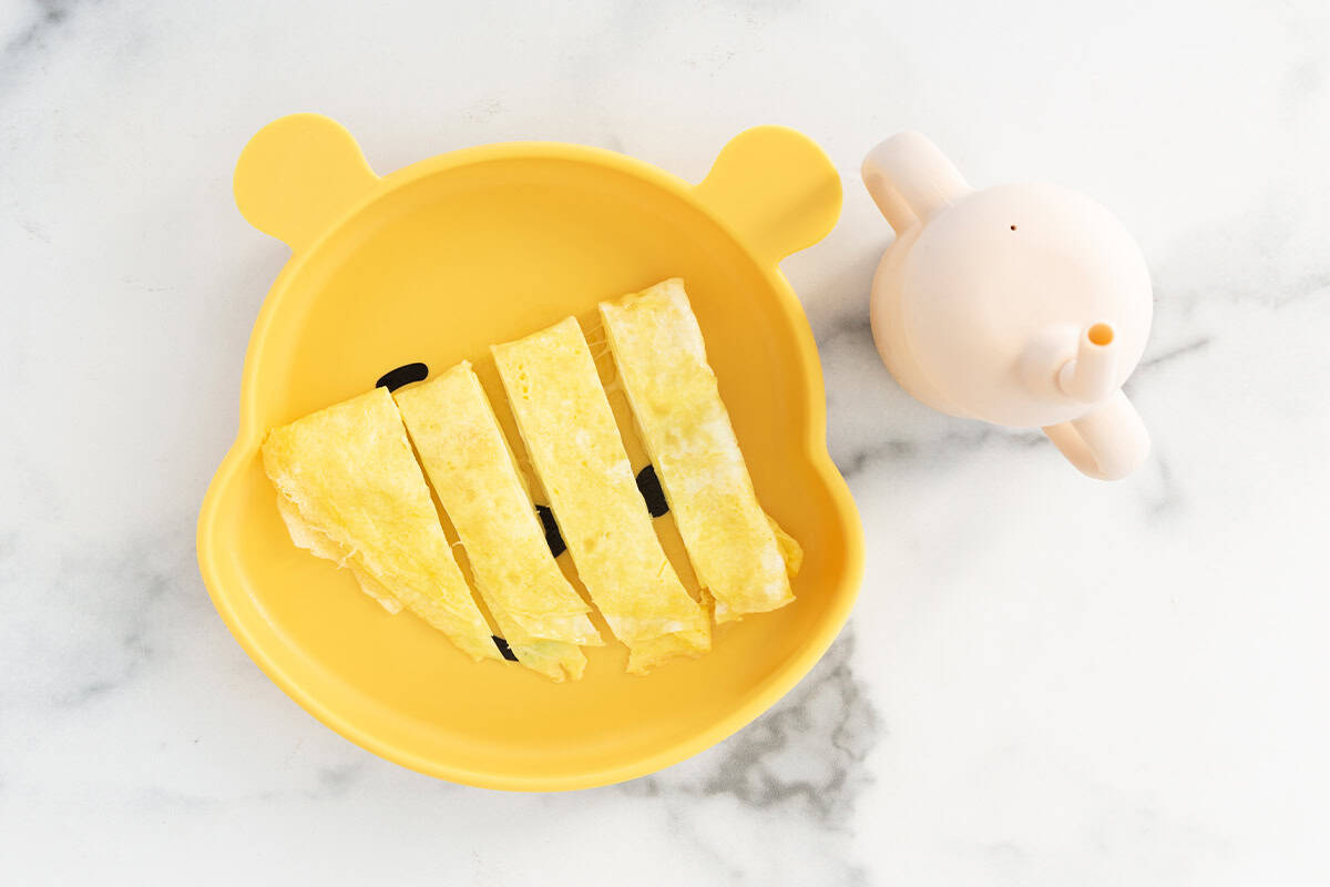 Baby omelette on yellow baby plate cut into strips.