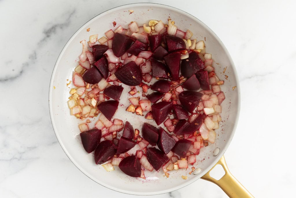 Beets and vegetables in pan for beet pasta sauce.