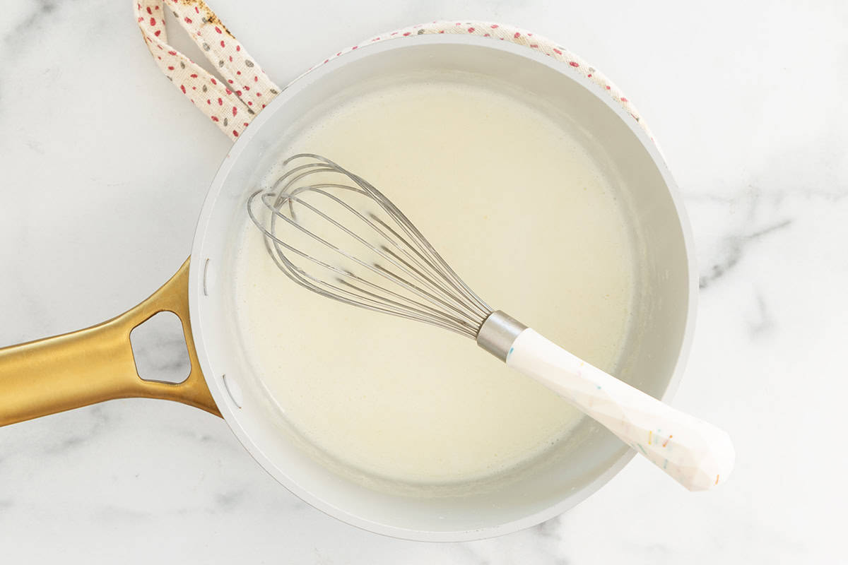 Whisk and sauce in pan for cheese sauce for pretzels.