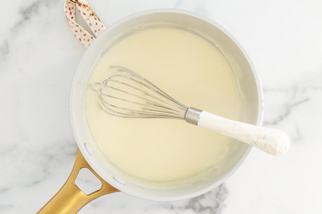 Whisk and sauce in pan for cheese sauce for pretzels.