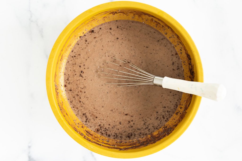 Whisking ingredients in yellow bowl for Chocolate Chia Pudding.