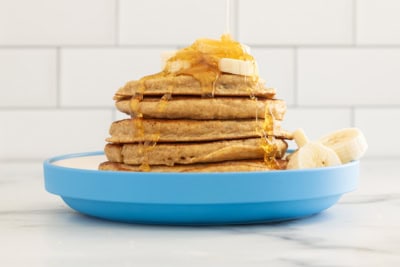 Stack of oatmeal protein pancakes on blue plate with syrup.