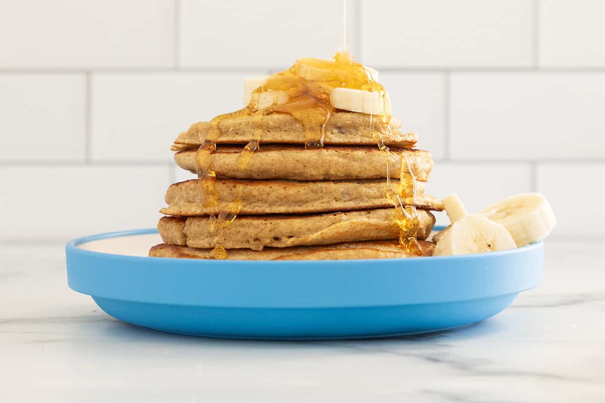 Stack of oatmeal protein pancakes on blue plate with syrup.  