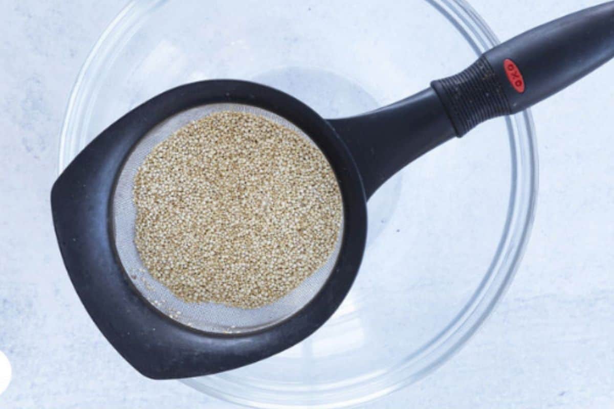 Quinoa in strainer over glass bowl. 