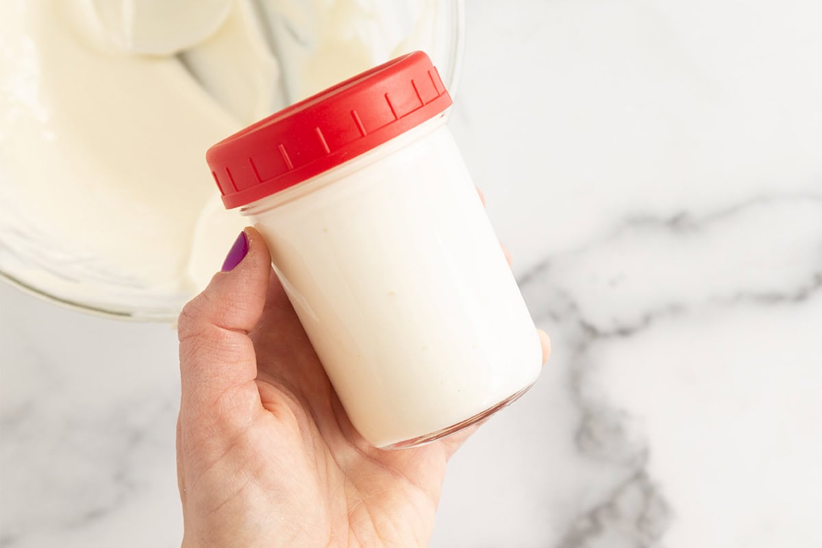 Cheesecake dip in glass jar with red lid.