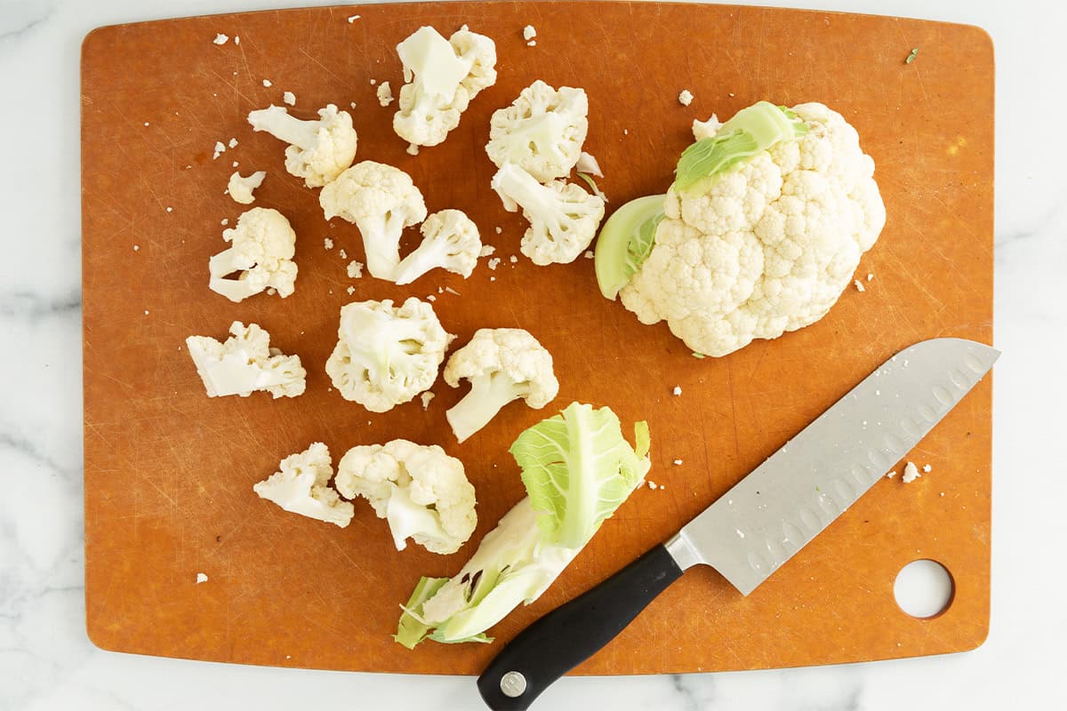 Cauliflower on cutting board with knife.