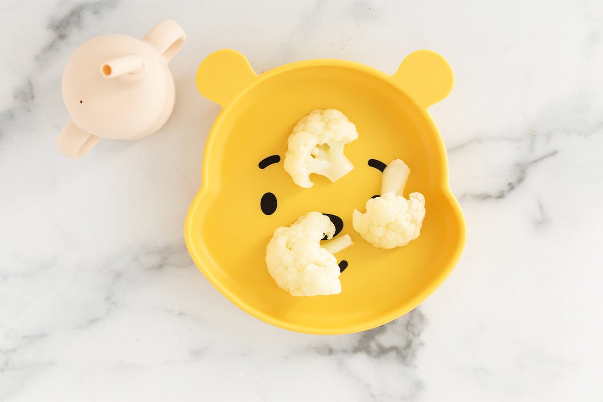 Cauliflower pieces on yellow kids plate.