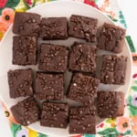 Chocolate snack cake cut into squares on plate.