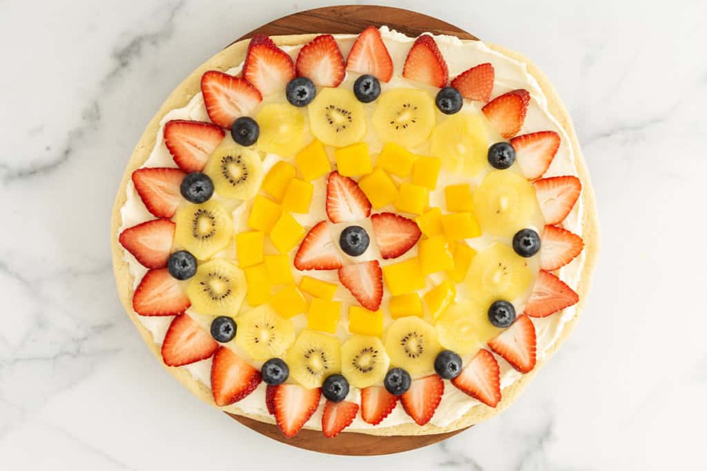 Fruit pizza on cutting board.