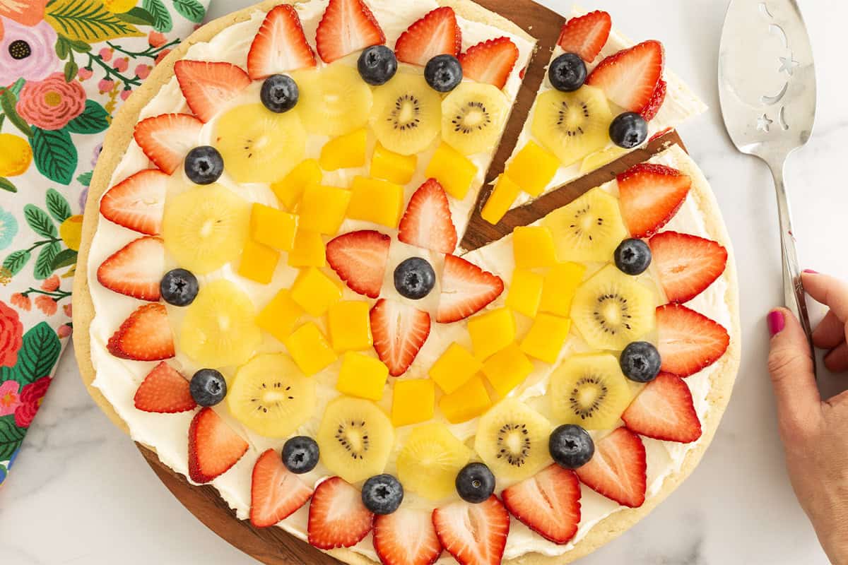 Fruit pizza with slice cut out.