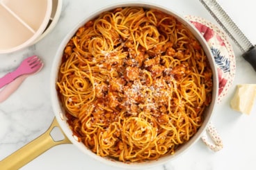 Spaghetti with sausage in pan with cheese on top.