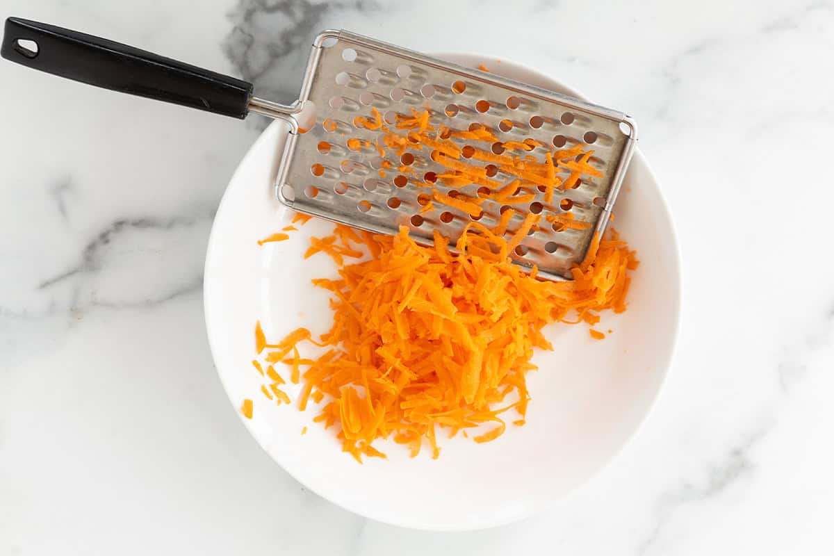 Carrot grated in bowl for carrot cake pancakes.