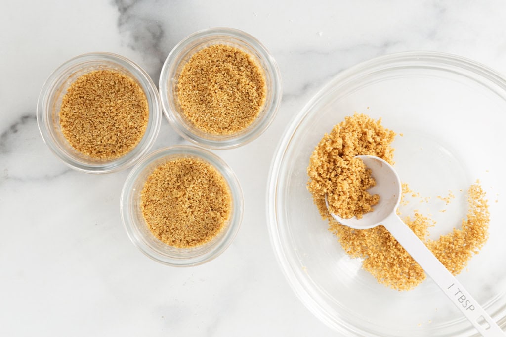 Graham cracker crumbs in containers for cheesecake cups.