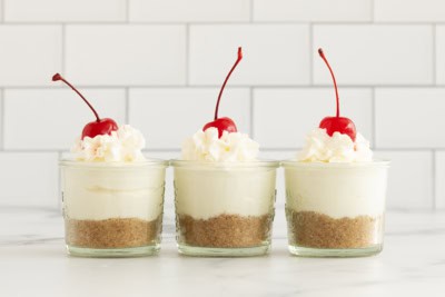 Three cheesecake cups on countertop.